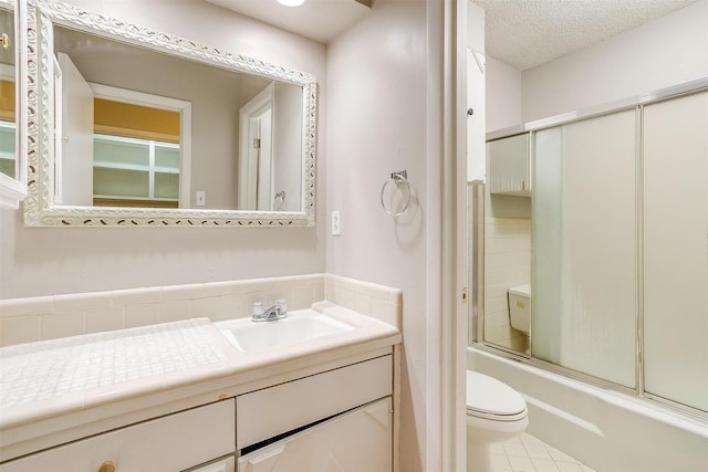 full bath with a textured ceiling, shower / bath combination with glass door, vanity, and toilet