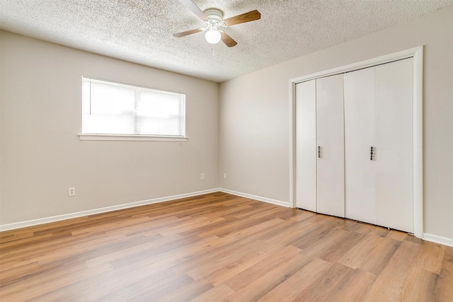 unfurnished bedroom featuring baseboards, light wood-style flooring, ceiling fan, a textured ceiling, and a closet