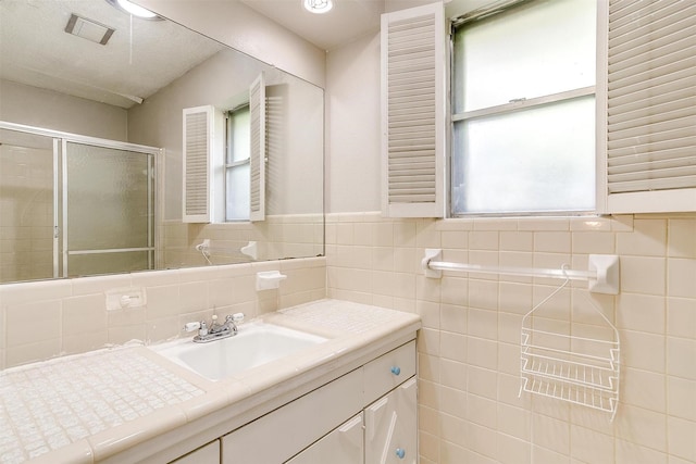 bathroom featuring visible vents, a stall shower, vanity, and tile walls