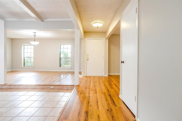 entryway featuring a textured ceiling, beam ceiling, and light hardwood / wood-style floors