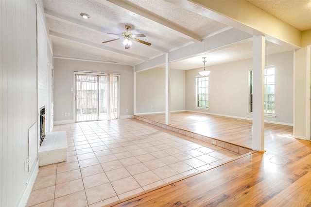 unfurnished living room featuring beam ceiling, light tile patterned flooring, a fireplace, and a textured ceiling