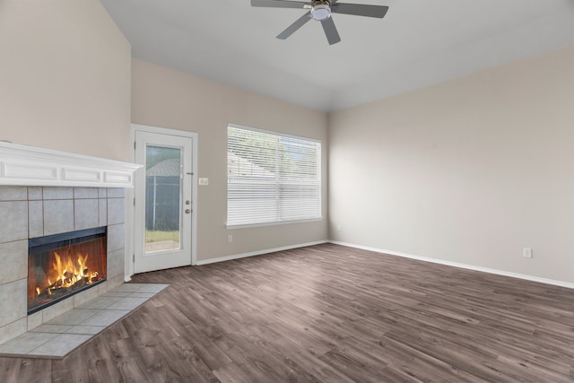 unfurnished living room with a wealth of natural light, ceiling fan, a tile fireplace, and hardwood / wood-style flooring