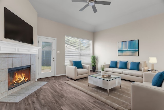 living room with ceiling fan, a tiled fireplace, and hardwood / wood-style flooring