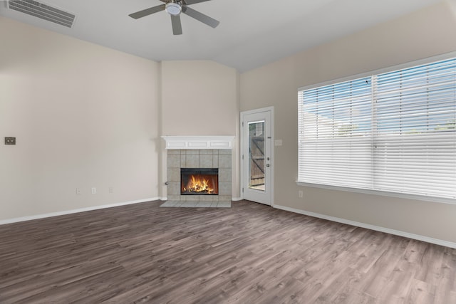 unfurnished living room with lofted ceiling, ceiling fan, hardwood / wood-style flooring, and a tiled fireplace