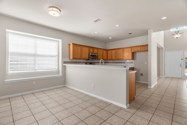 kitchen with tasteful backsplash, kitchen peninsula, light tile patterned floors, and sink