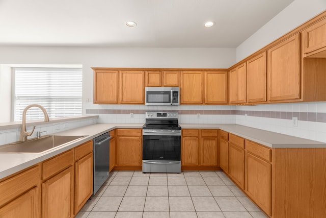 kitchen with appliances with stainless steel finishes, backsplash, light tile patterned flooring, and sink