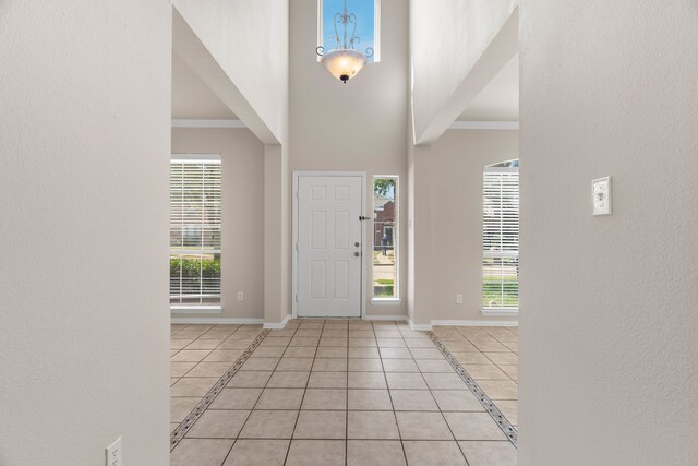 tiled foyer entrance with a wealth of natural light, crown molding, and a towering ceiling