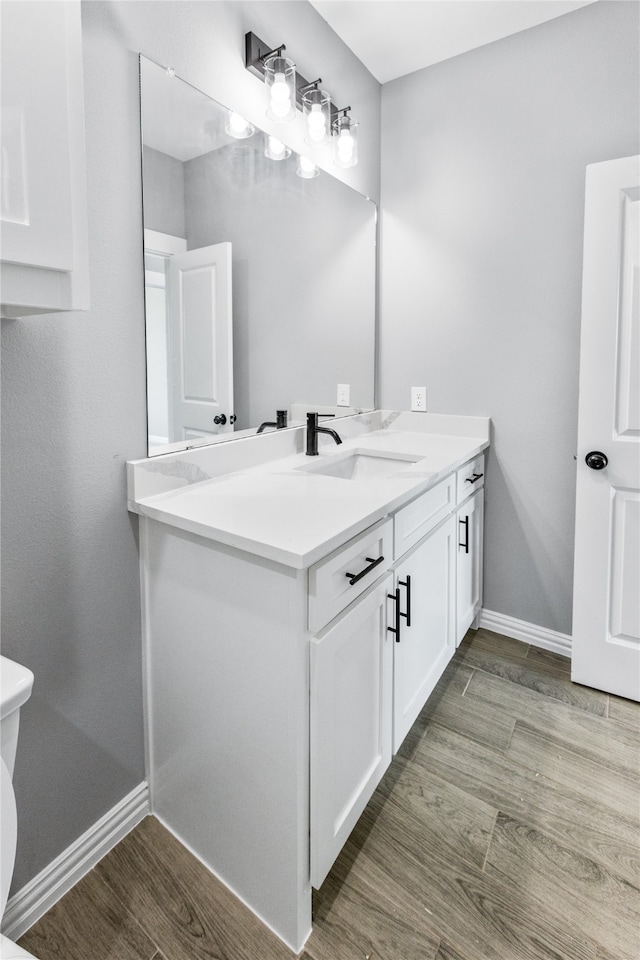 bathroom with vanity, toilet, and hardwood / wood-style flooring