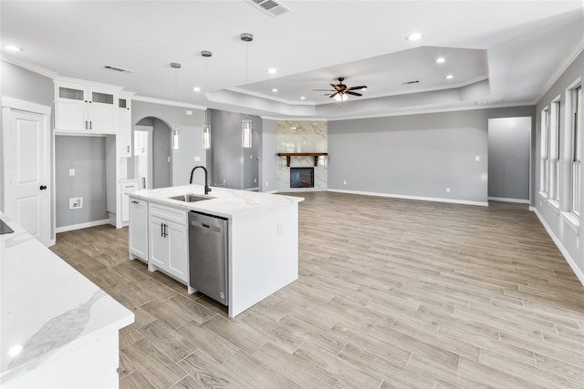 kitchen featuring dishwasher, a raised ceiling, ceiling fan, and a stone fireplace