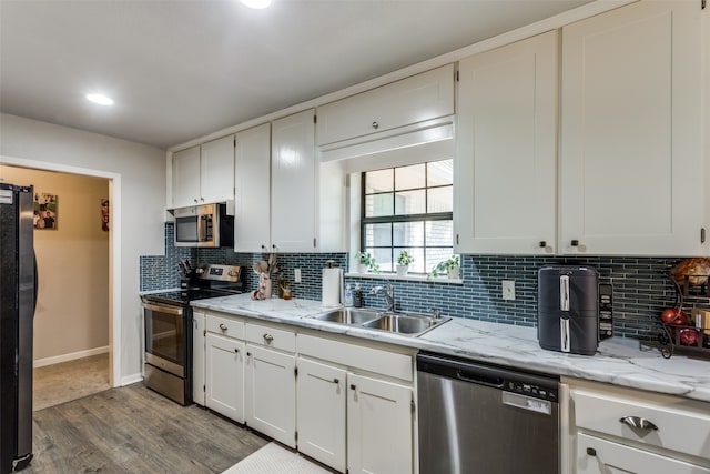 kitchen with appliances with stainless steel finishes, hardwood / wood-style floors, sink, and tasteful backsplash