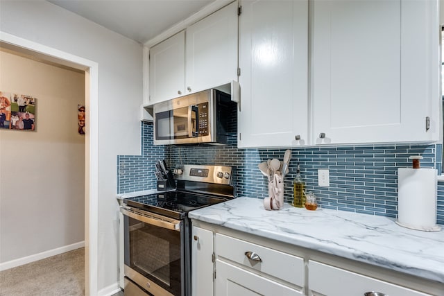 kitchen featuring backsplash, light stone counters, stainless steel appliances, and white cabinets