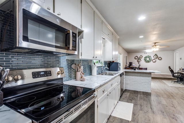 kitchen featuring light wood-type flooring, white cabinets, kitchen peninsula, stainless steel appliances, and ceiling fan