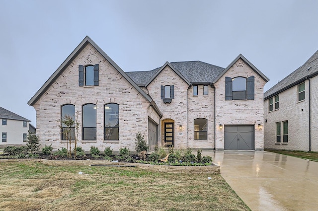 french country style house with a front lawn and a garage