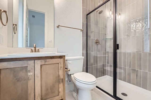 bathroom featuring vanity, a shower with shower door, and toilet