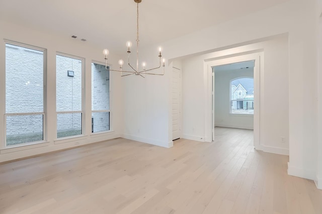 unfurnished dining area with a notable chandelier and light wood-type flooring