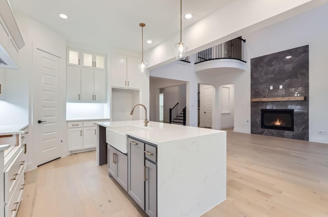 kitchen featuring hanging light fixtures, white cabinetry, sink, and an island with sink