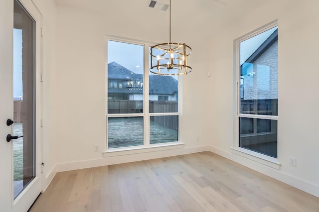 unfurnished dining area with a chandelier and light hardwood / wood-style flooring