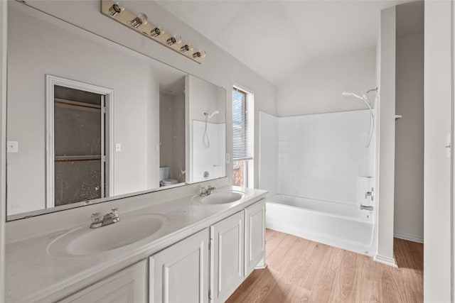 bathroom with vaulted ceiling, hardwood / wood-style flooring, vanity, and shower / bath combination