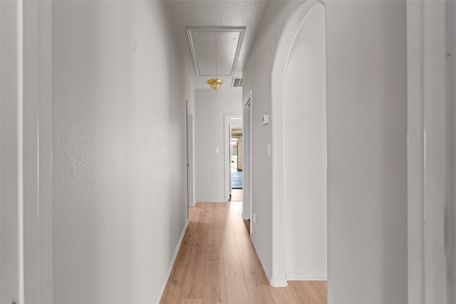 hall with a textured ceiling and light hardwood / wood-style floors