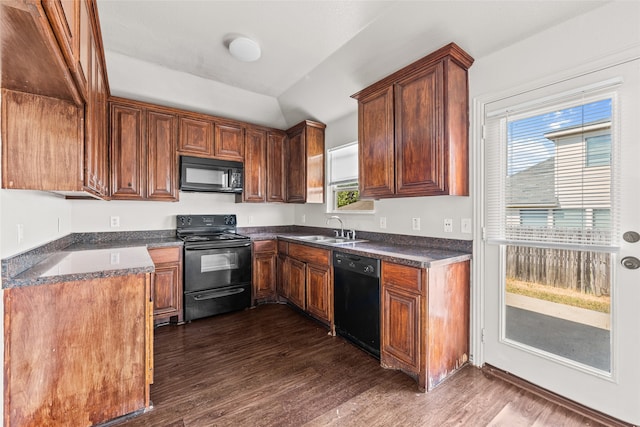 kitchen featuring black appliances, dark hardwood / wood-style flooring, dark stone counters, and sink