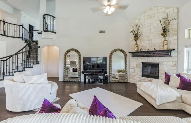 living room with dark wood-type flooring, ceiling fan, high vaulted ceiling, and a fireplace