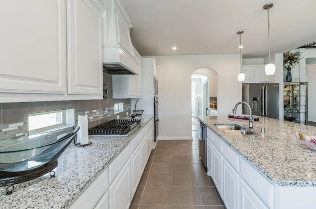 kitchen with tile patterned floors, appliances with stainless steel finishes, white cabinetry, sink, and tasteful backsplash