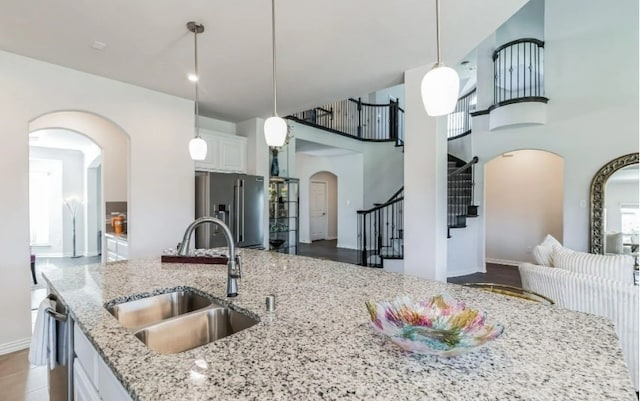 kitchen with white cabinets, light stone countertops, stainless steel appliances, and sink