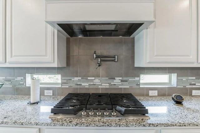 kitchen featuring white cabinets, light stone counters, and decorative backsplash