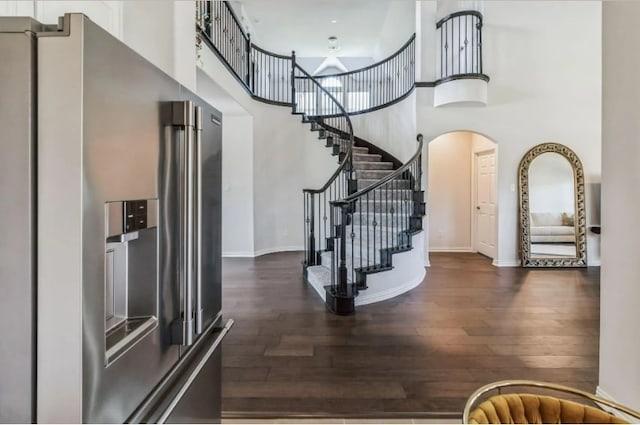 interior space with a towering ceiling and dark hardwood / wood-style floors