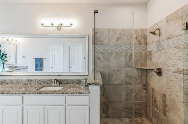 bathroom with tiled shower and vanity