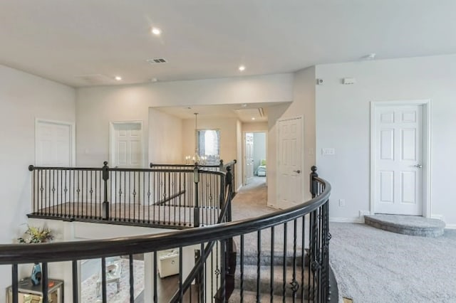 hallway with carpet and a notable chandelier