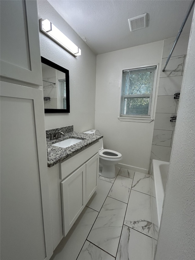 full bathroom with tiled shower / bath, vanity, toilet, and a textured ceiling