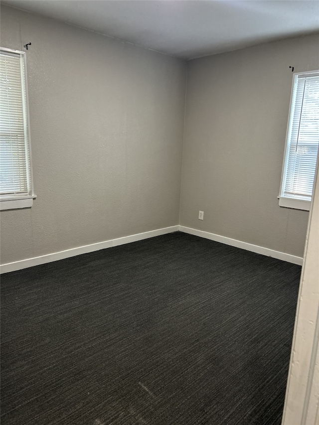 unfurnished room with dark carpet