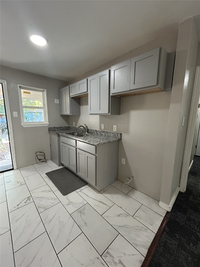 kitchen with gray cabinets, dark stone counters, and sink