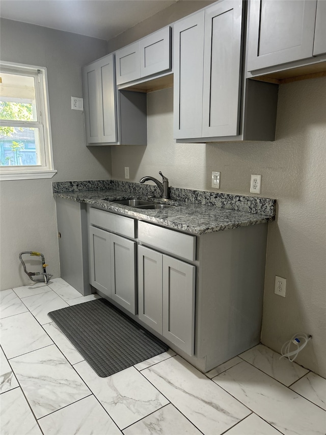 kitchen featuring gray cabinetry, dark stone countertops, and sink