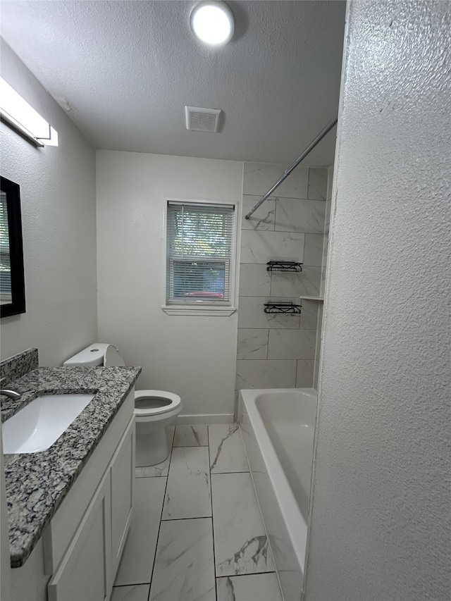 full bathroom with a textured ceiling, tiled shower / bath combo, vanity, and toilet