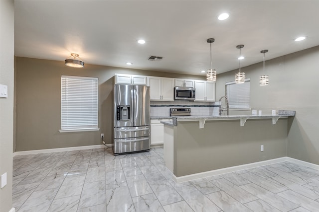 kitchen featuring tasteful backsplash, a breakfast bar, stainless steel appliances, kitchen peninsula, and white cabinetry