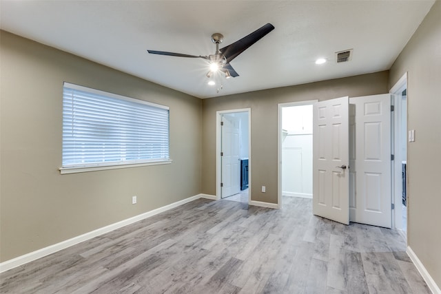 unfurnished bedroom with multiple windows, a walk in closet, ceiling fan, and light hardwood / wood-style flooring