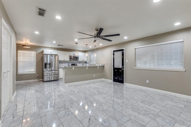 kitchen featuring white cabinets, kitchen peninsula, ceiling fan, appliances with stainless steel finishes, and light tile patterned flooring