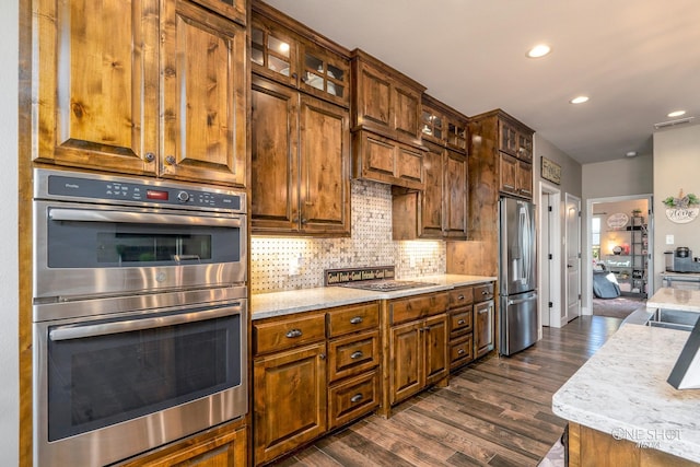 kitchen featuring dark hardwood / wood-style flooring, light stone countertops, stainless steel appliances, and tasteful backsplash