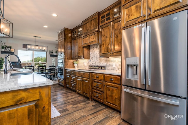 kitchen featuring sink, hanging light fixtures, light stone countertops, appliances with stainless steel finishes, and dark hardwood / wood-style flooring