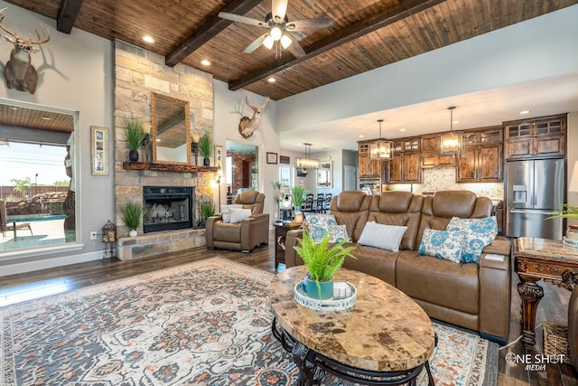 living room featuring wooden ceiling, a stone fireplace, beamed ceiling, ceiling fan with notable chandelier, and hardwood / wood-style flooring