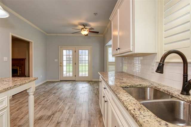 kitchen with white cabinets, light hardwood / wood-style floors, sink, ceiling fan, and decorative backsplash