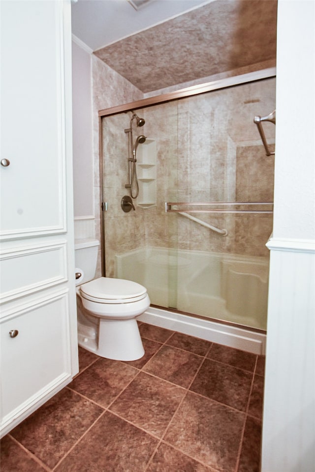 bathroom featuring toilet, an enclosed shower, and tile patterned flooring