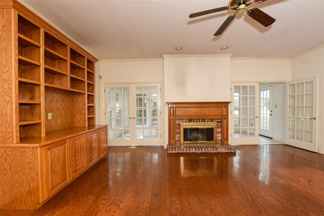 unfurnished living room featuring crown molding, dark hardwood / wood-style floors, a brick fireplace, and french doors