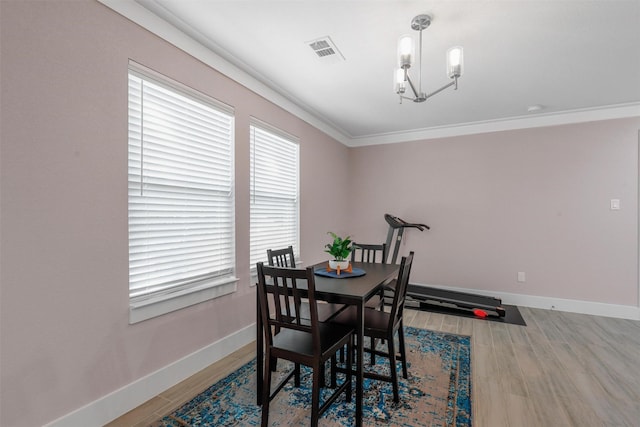 dining room with crown molding, visible vents, wood finished floors, a chandelier, and baseboards