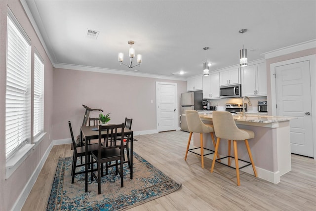 dining space with crown molding, a notable chandelier, light wood finished floors, visible vents, and baseboards