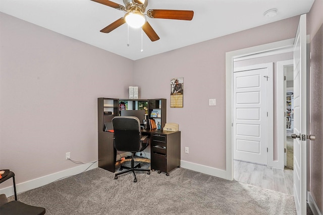 office featuring baseboards, ceiling fan, and light colored carpet