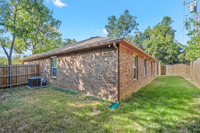 view of property exterior with central AC, brick siding, a lawn, and a fenced backyard