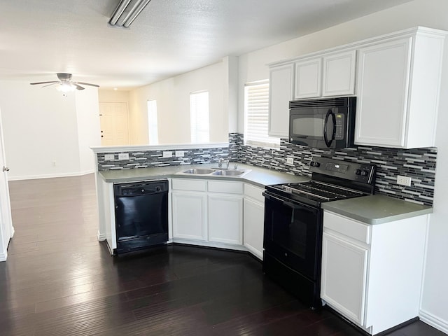 kitchen featuring dark wood-style flooring, a sink, a peninsula, and black appliances